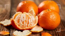 mandarins on a wooden table being peeled to support ideas on how to use orange peel in your garden