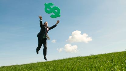 A man in a business suit chases a dollar sign floating above him.