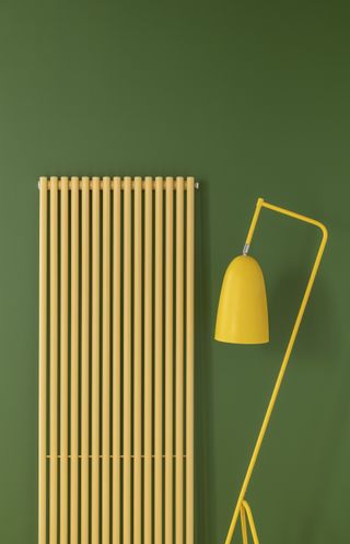 Yellow vertical radiator on green wall with yellow floor lamp