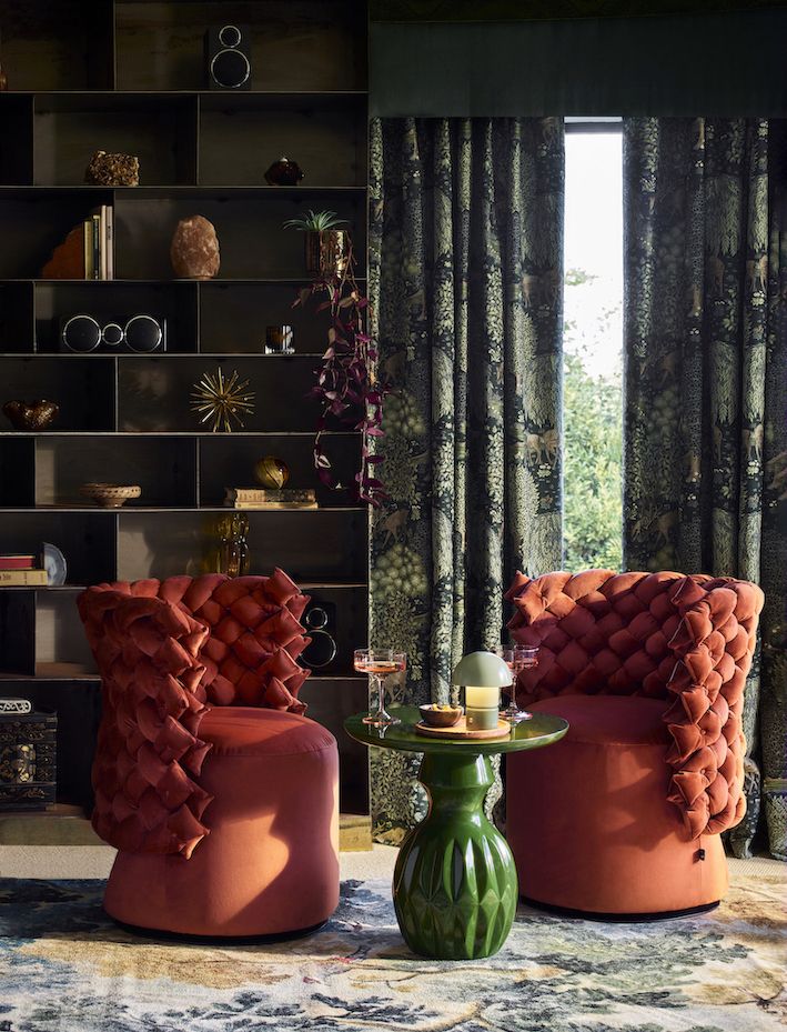 Image of two red accent chairs with braided backs and a green table in between the two.