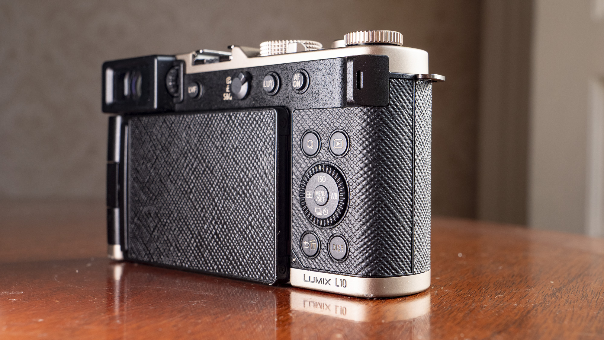 Rear of the Titanium Gold special edition of the Panasonic Lumix L10 compact camera, on an antique wooden table 