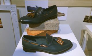 Black leather shoes stand on a wooden plinth