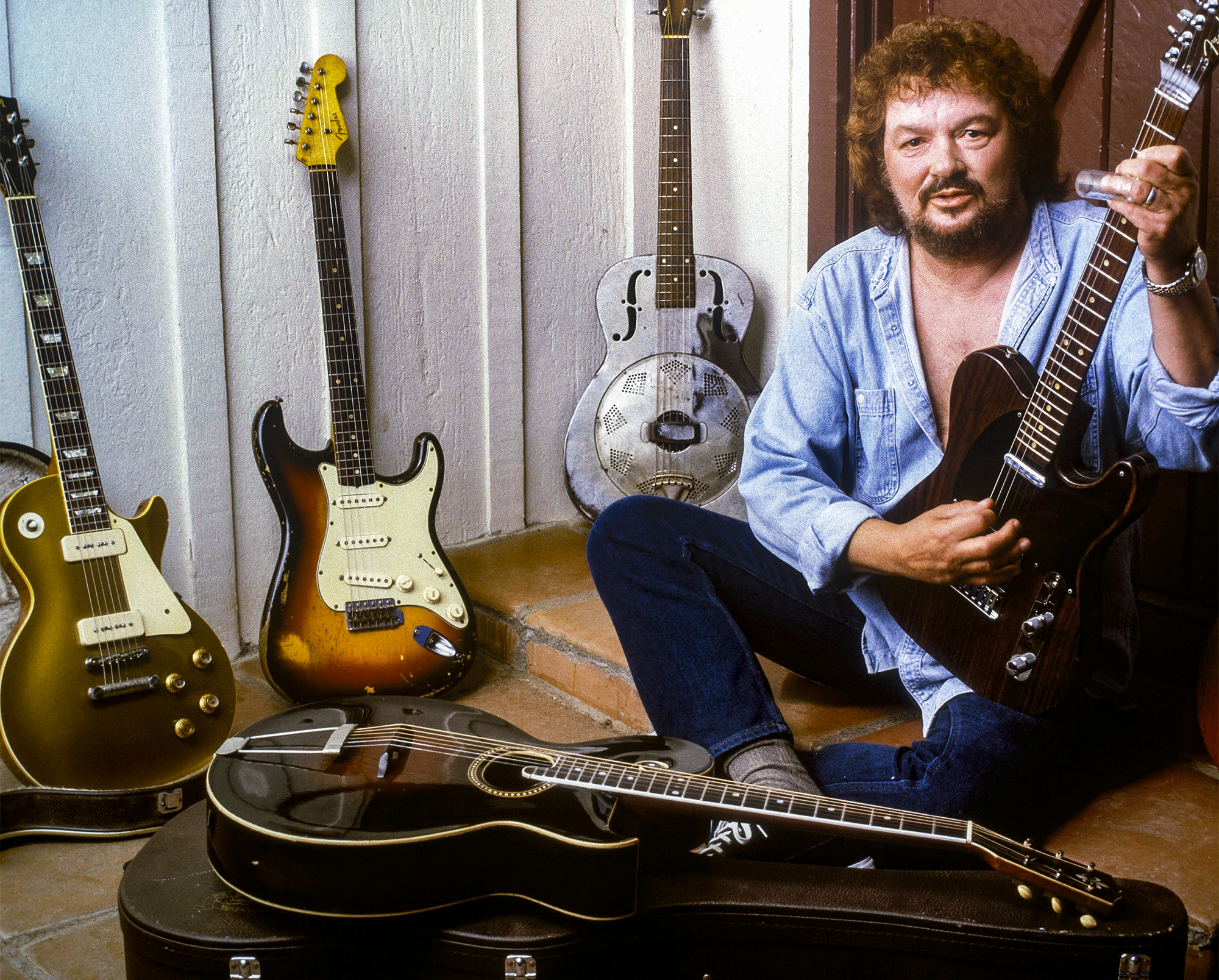 Delaney Bramlett poses at home in the 1990s with guitars from his collection including Duane Allman&amp;rsquo;s 1961 Fender Strat, George Harrison&amp;rsquo;s 1968 Rosewood Telecaster and the 1913 Gibson Style O (front) formerly owned by Eric Clapton and Harrison