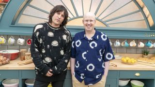 Noel Fielding in a black and white jumper and Matt Lucas in a blue and white shirt stand in the tent on The Great British Bake Off.