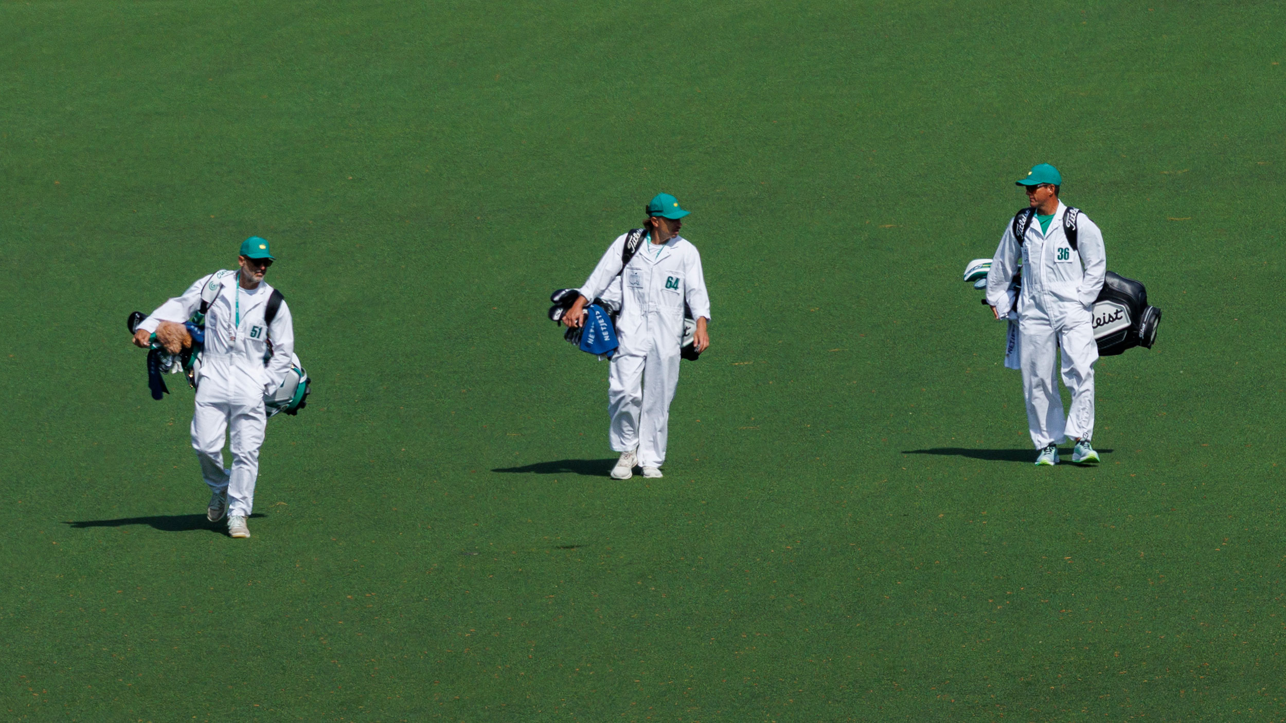 a group of caddies walking down the 9th fairway at augusta national