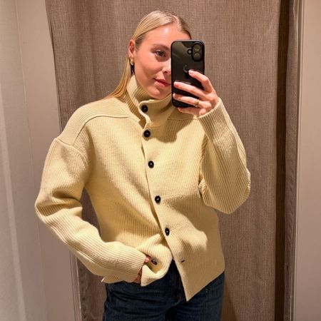 Woman wears yellow funnel-neck collar cardigan with black buttons