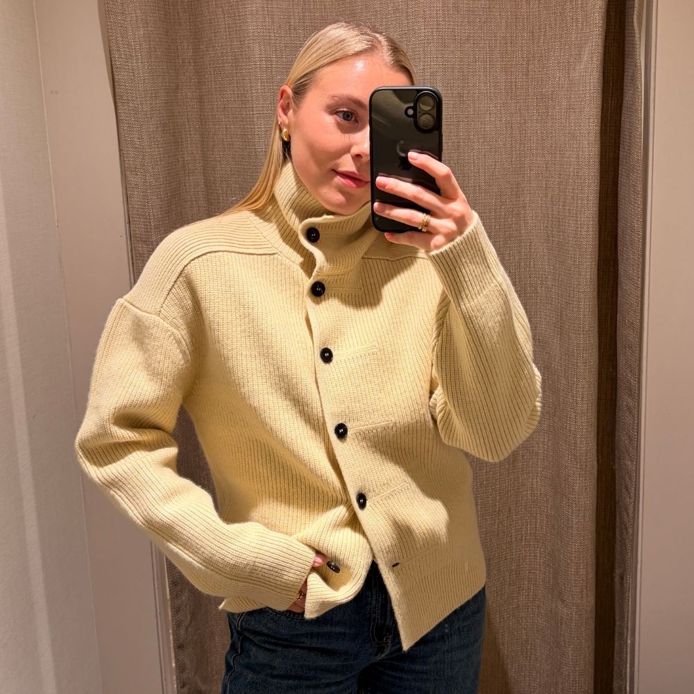Woman wears yellow funnel-neck collar cardigan with black buttons
