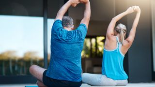 Best exercises for lower back pain: Image shows two people stretching outdoors on yoga mat