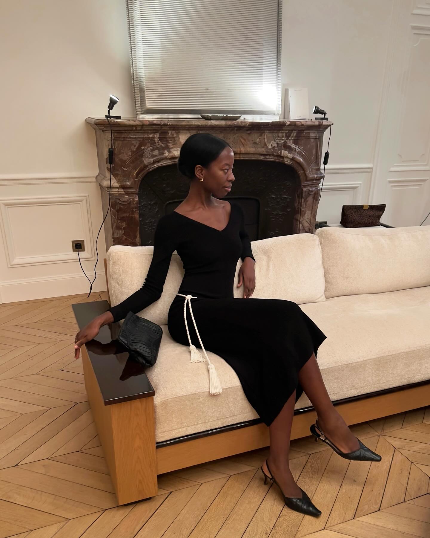 A woman in a black dress on a white couch.