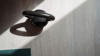 Kettlebell sitting on wooden floor next to yoga mat