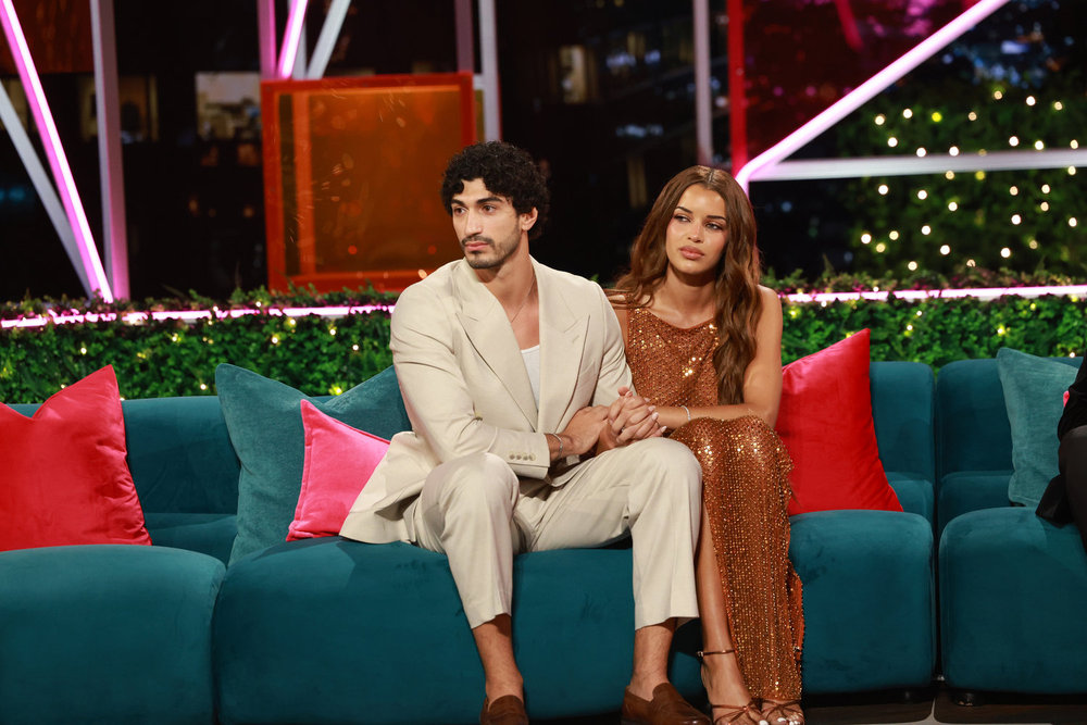 Zacharias Georgiou and Kayda Reese Bosse hold each other while sitting solo on a teal couch at the love island usa season 8 reunion