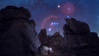 Three bright stars in a line in the sky above a rocky outcrop. 