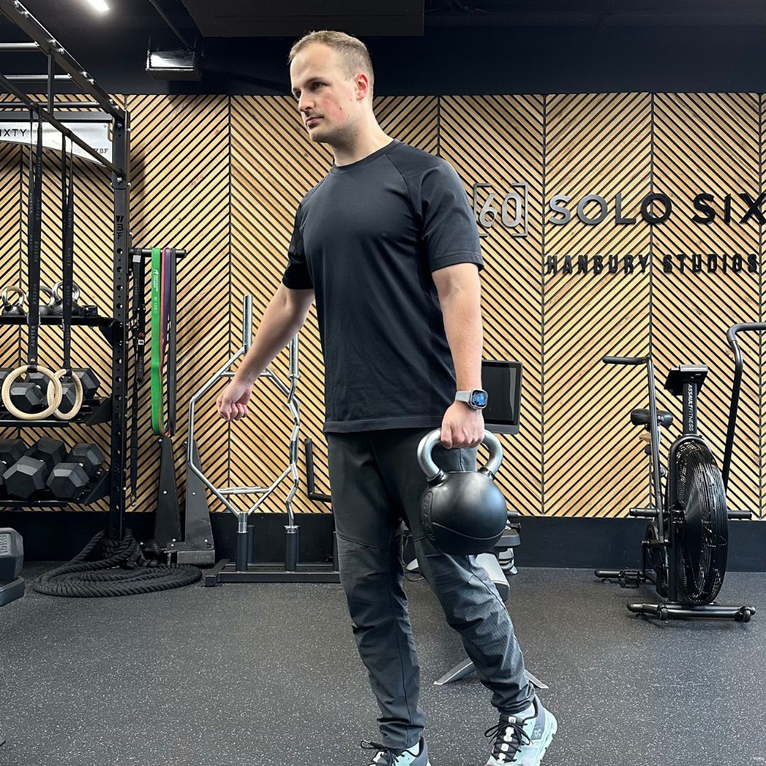 Personal trainer Ollie Thompson demonstrating a suitcase carry
