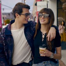Nicholas Galitzine as Hayes Campbell and Anne Hathaway as Soléne, walking down a busy sidewalk as onlookers take pictures, in the rom-com 'The Idea of You'