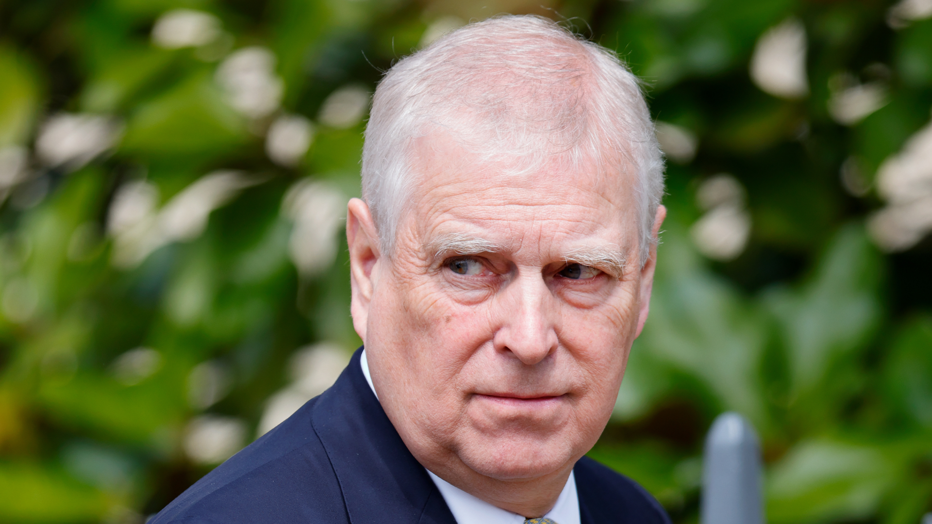 Prince Andrew wearing a blue suit and scowling