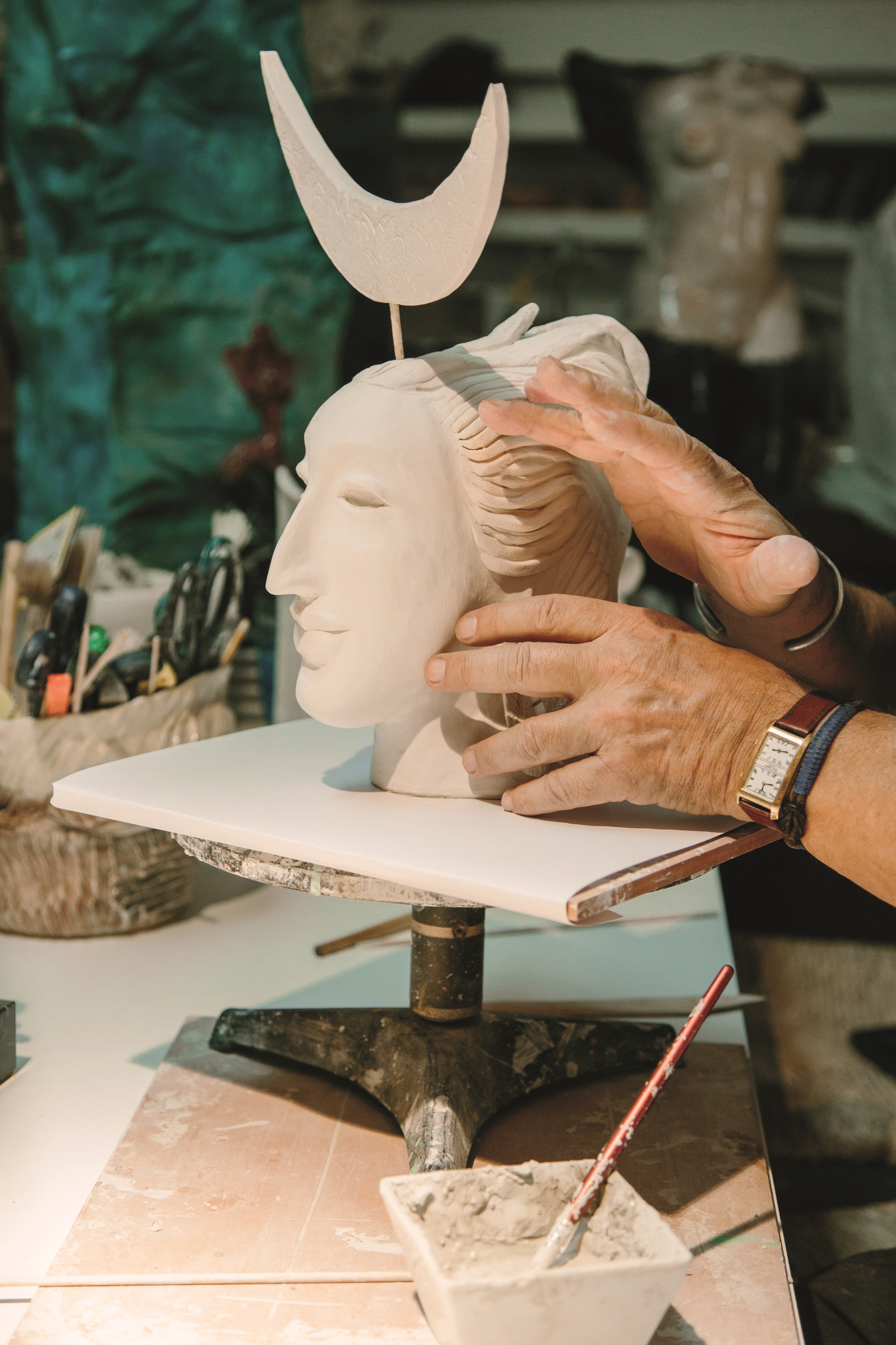 The hands of a sculptor are captured at work as he refined a face cast from clay.