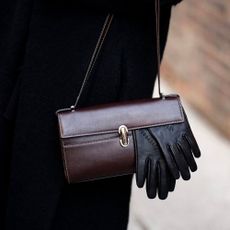 @alexisbadiyi wearing a brown leather bag and black leather gloves