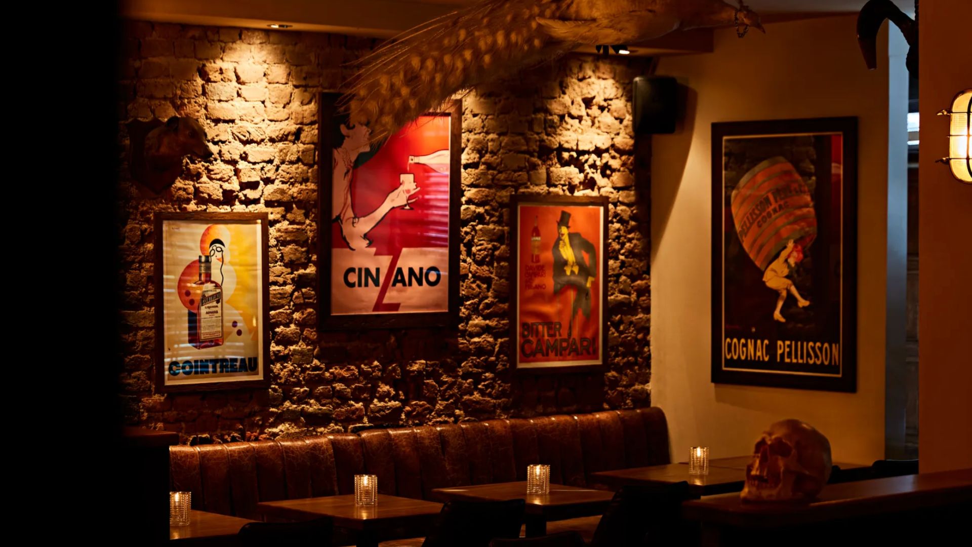 an image of the interior of the bar Satan's Whiskers showing an exposed brick wall with banquette tables against it