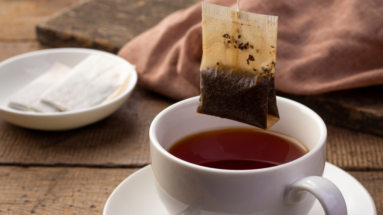 Air fryer tea bag cleaning hack: Tea bag being dipped into a white mug