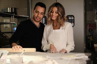 Victor Rasuk and Nathalie Kelley stand in a kitchen, ready to bake