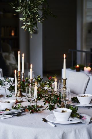 Christmas table scene with holly and white candles by Sims Hilditch