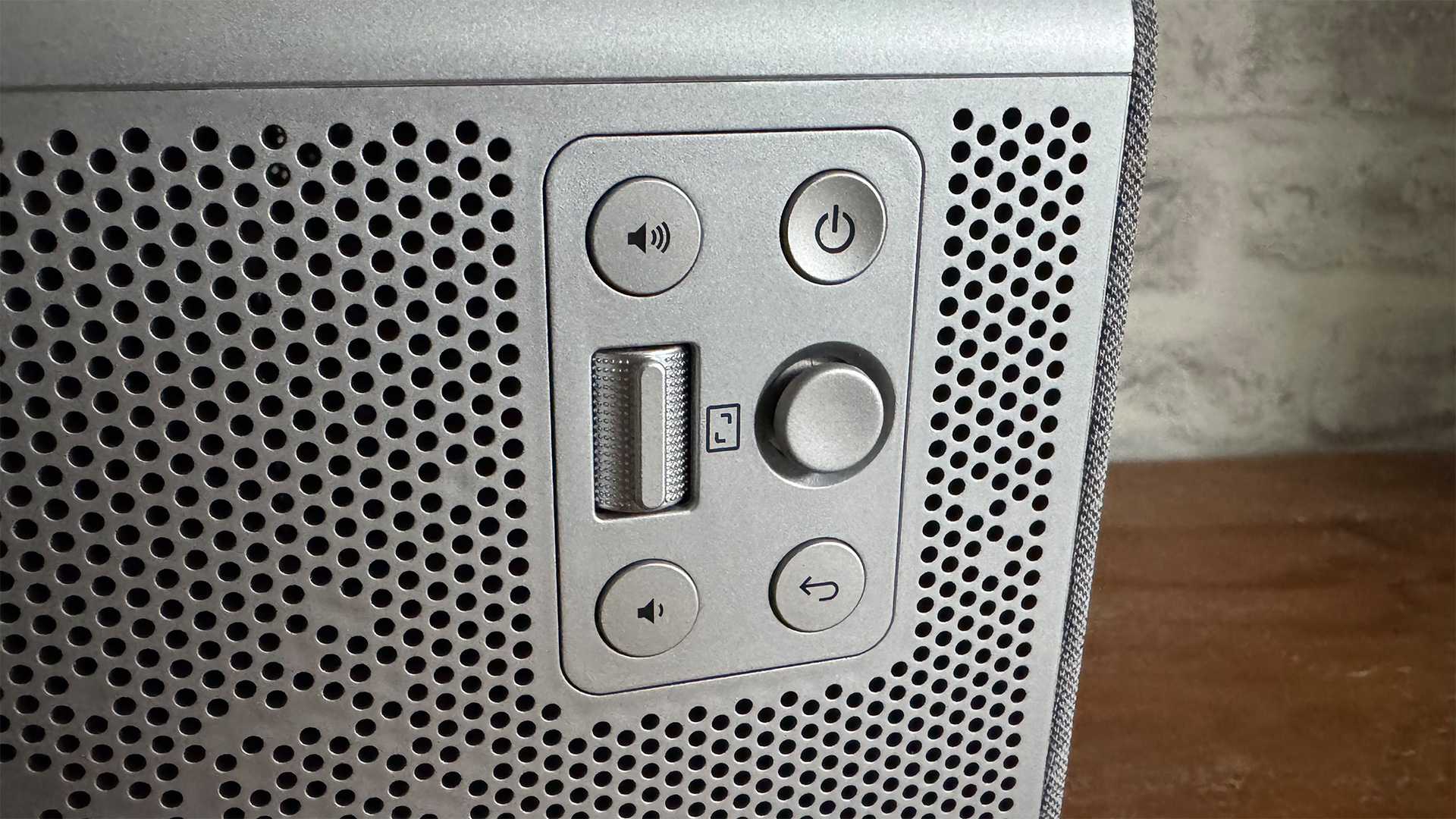 BenQ TK705i home cinema projector on wooden sideboard in front of white brick wall detail of control buttons