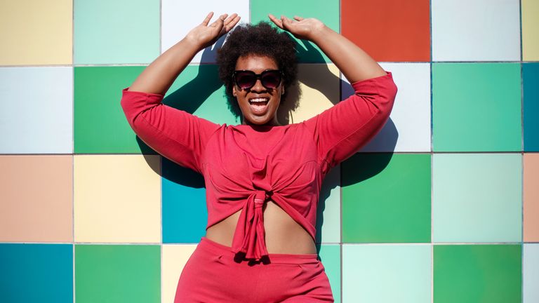 woman wearing a fun red outfit in front of a color wall