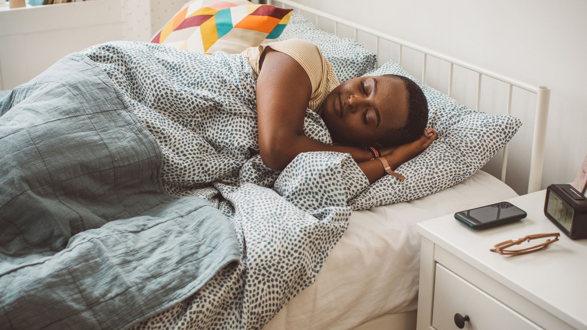 A student sleeps in a bed in a dorm room.