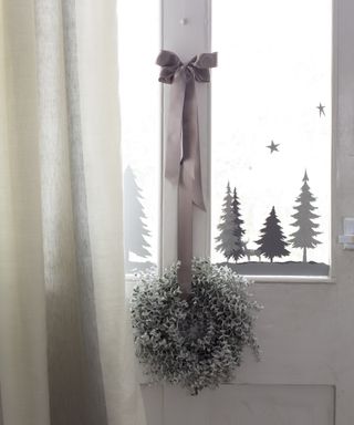 Christmas window decor ideas with grey and white tree and snowflake stickers in the window panel of a white door