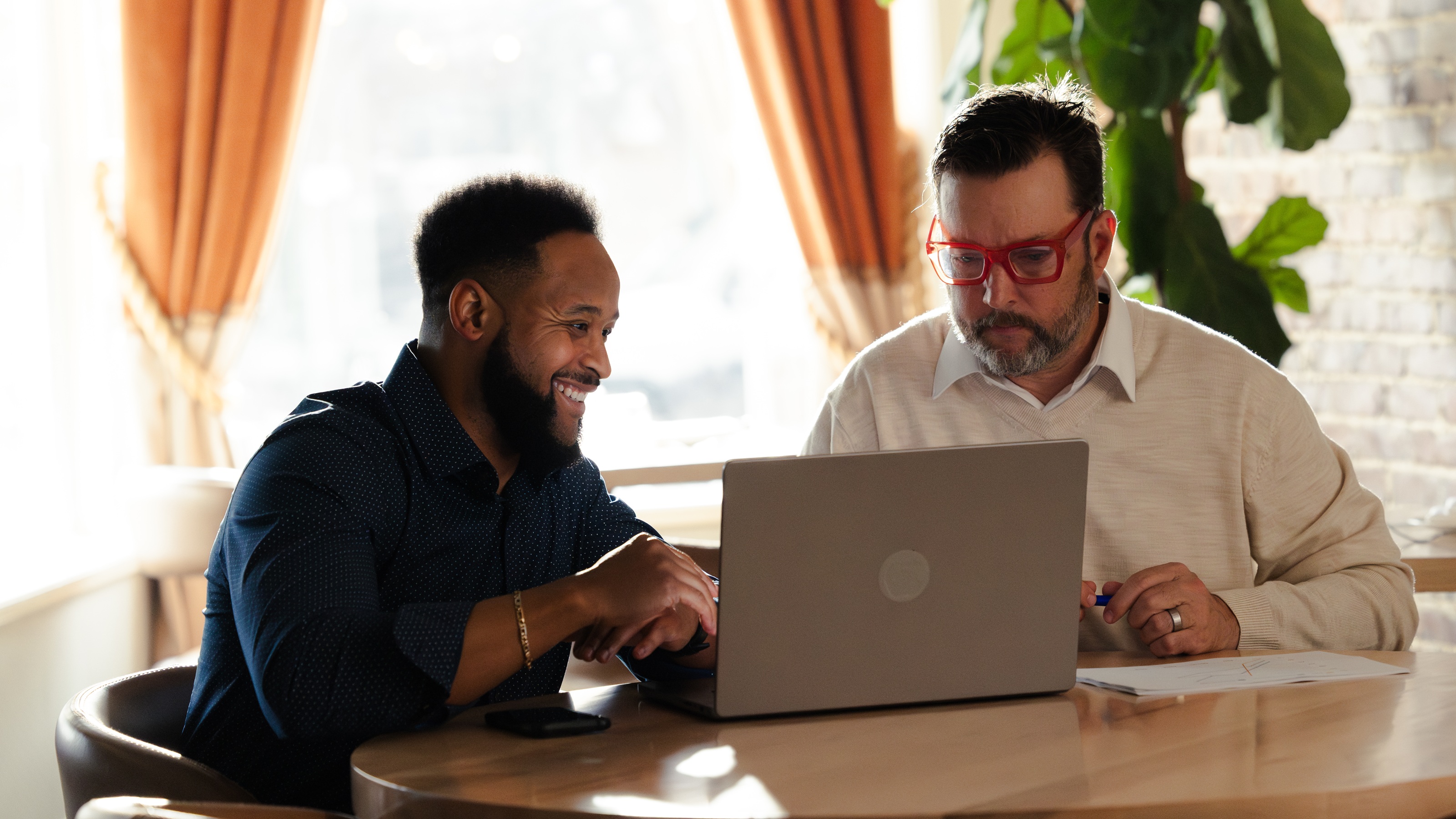 Two business partners go over their plans at a table with a laptop.
