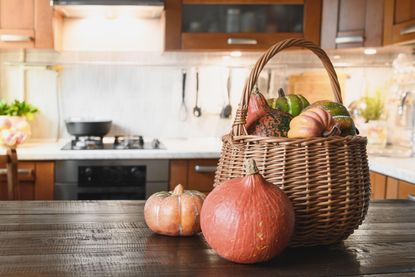 A woven basket full of pumpkins on a kitchen countertop