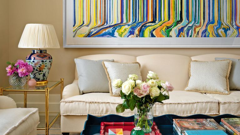 cream living room with cream sofas and statement multicolored artwork and blue coffee table