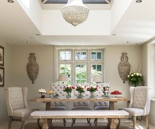 elegant dining room with upholstered cream button back chairs and dining bench with roof lantern over the table