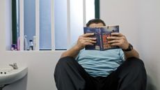 A man reads a book in a jail cell