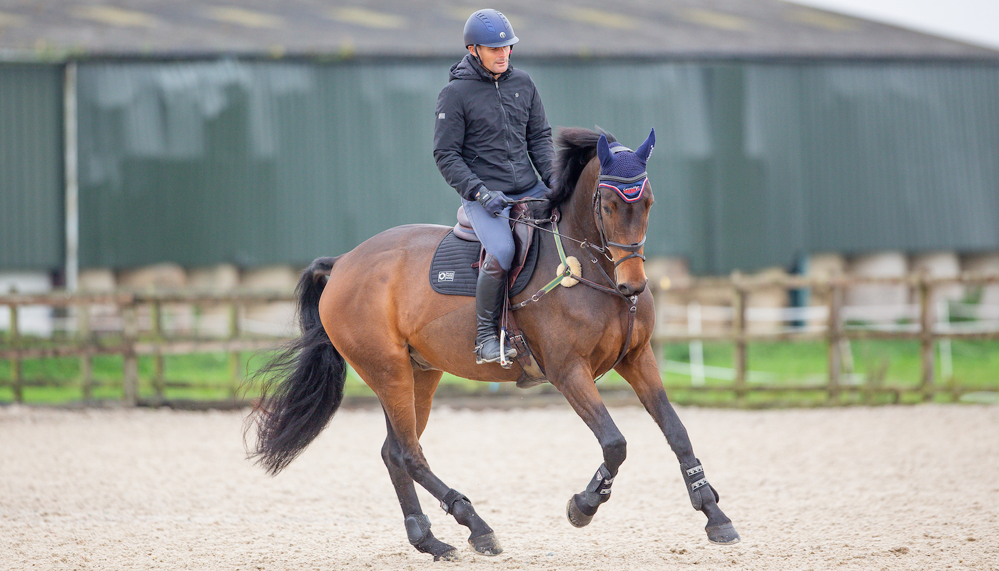 Alex Bragg cantering bay horse before jump training