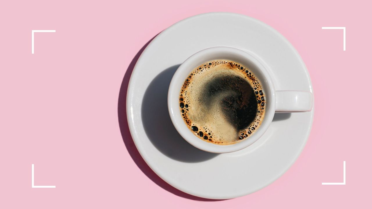 Cup of black coffee in white china mug sitting on light pink background, representing the benefits of coffee