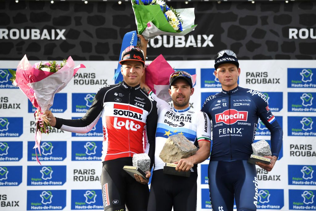 ROUBAIX FRANCE OCTOBER 03 LR Florian Vermeersch of Belgium and Team Lotto Soudal on second place stage winner Sonny Colbrelli of Italy and Team Bahrain Victorious with his cobblestone trophy and Mathieu Van Der Poel of Netherlands and Team AlpecinFenix on third place celebrate on the podium during the podium ceremony after during the 118th ParisRoubaix 2021 Mens Eilte a 2577km race from Compigne to Roubaix ParisRoubaix on October 03 2021 in Roubaix France Photo by Tim de WaeleGetty Images