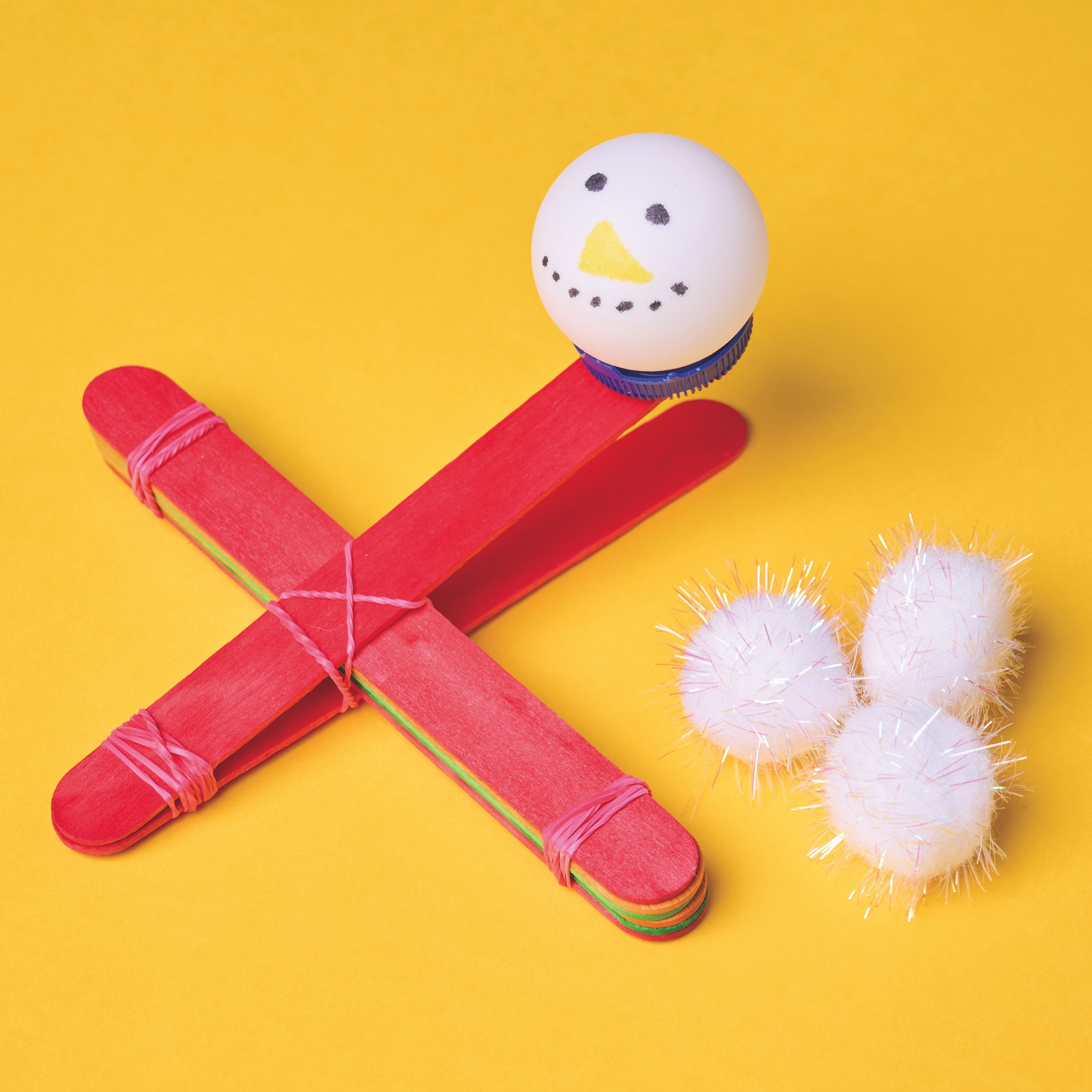 Snowball thrower made of a ping pong ball, a bottle cap and lolly sticks