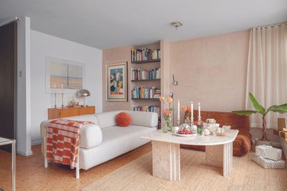 A pale pink living room with a white sofa and marble coffee table