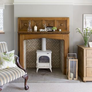 white wood burning stove in tiled fireplace with wooden mantle