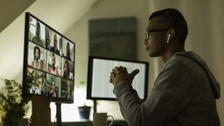 A man sat in front of two monitors while in a video meeting