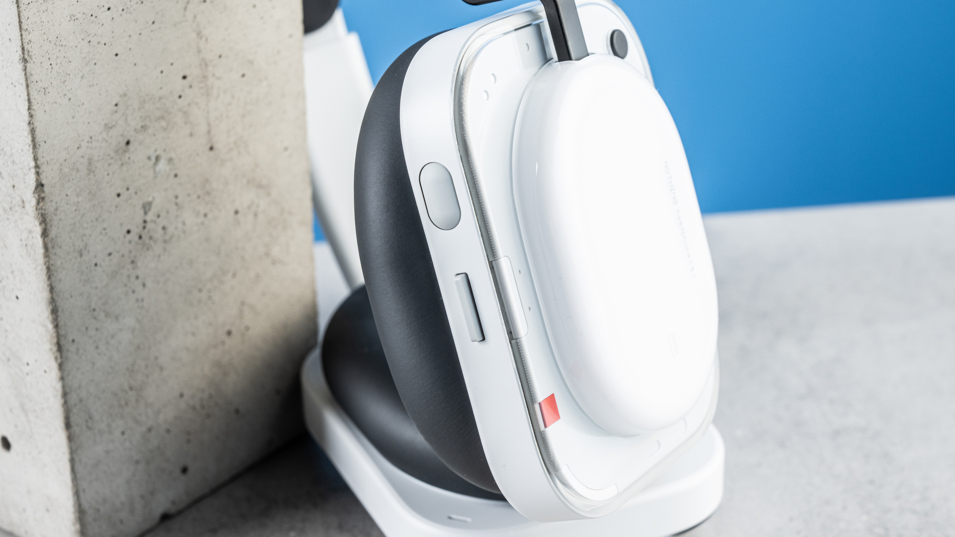 the nothing headphone (a) photographed against the blue tom's guide background, showing the transparent and white ear cups with red accents, the padded headband, and the accessories including 3.5mm jack