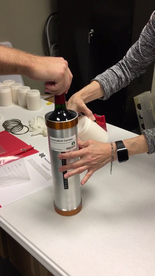 Researchers pack up a bottle of wine to ship to the International Space Station.