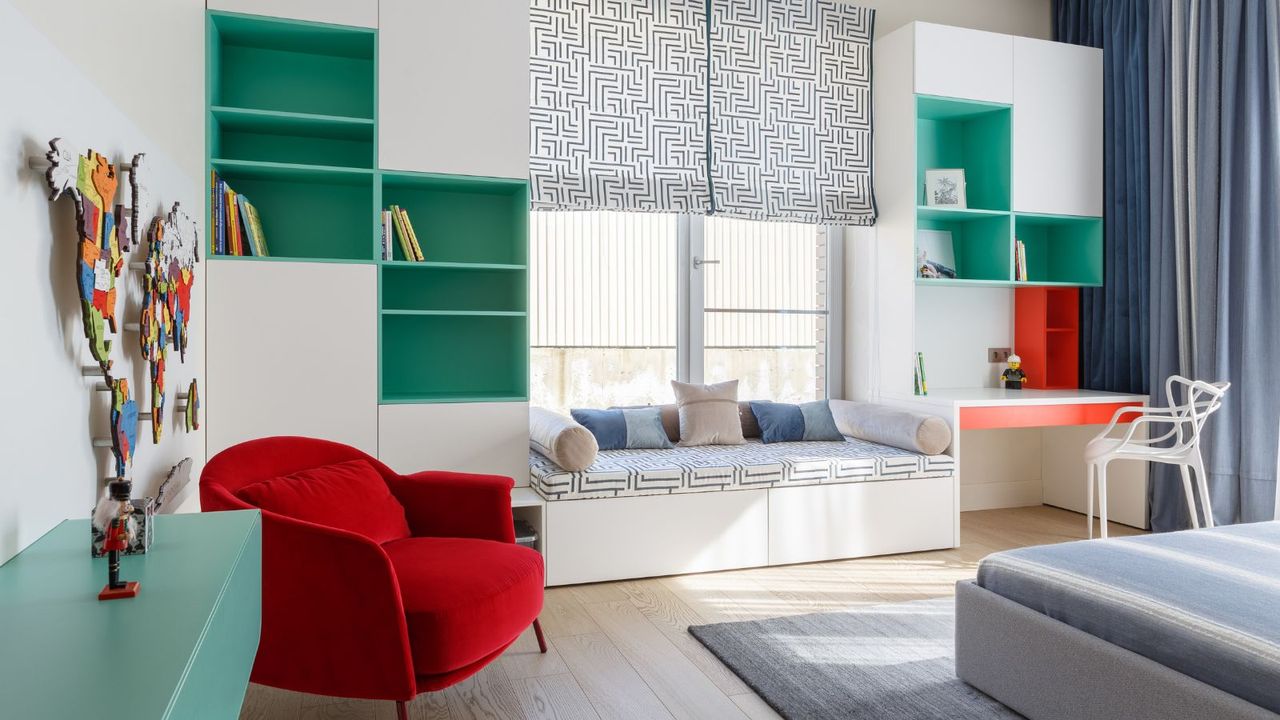 A minimalist bedroom with window bench, tall shelving with green painted backs, red statement chair and clean lines with minimal items