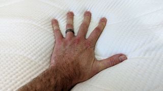 Hand pressing firmly down on top surface of Koala SE mattress