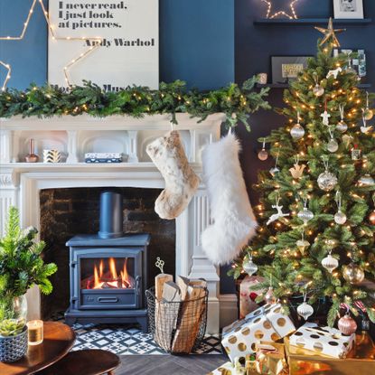 Christmas tree with presents on the floor, next to traditional fireplace with stockings
