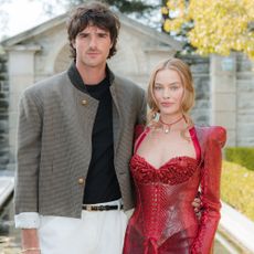 Margot Robbie wears a red minidress posing with Jacob Elordi
