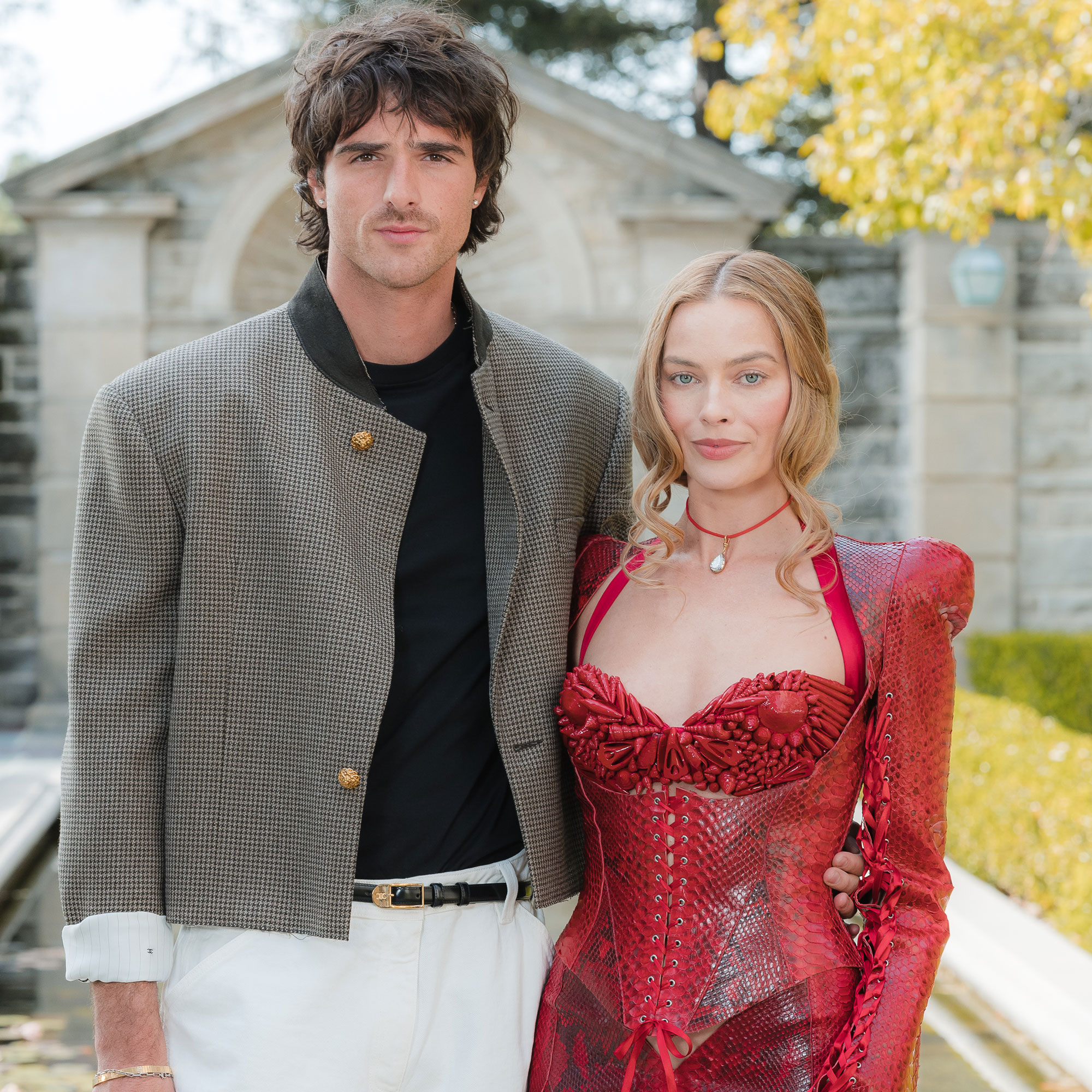 Margot Robbie wears a red minidress posing with Jacob Elordi