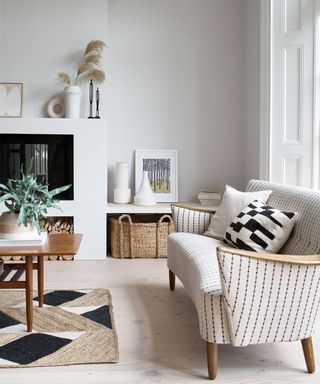 White living room with white walls and floors and accents of black with large fireplace