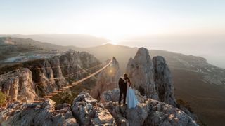 Bride and Groom hug each other on the edge of a precipice at sunset